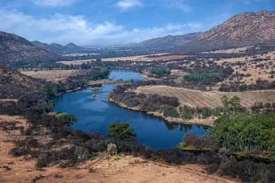 Aerial view of the Vaal River meandering through the Vredefort Dome landscape with hills, farmland and riverine vegetation in North West and Free State, South Africa.
