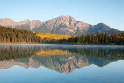Patricia Lake at sunrise with mountain reflection, mist, and autumn forest