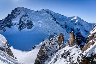 Mont Blanc summit with glacier and surrounding peaks seen from the Chamonix side, framed by rocky alpine spires.