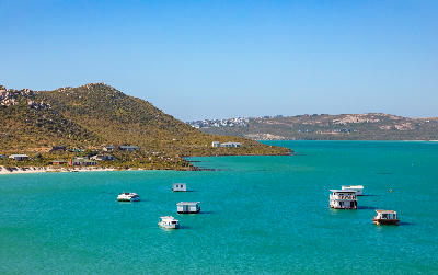 Houseboats floating on the turquoise waters of Kraalbaai in Langebaan Lagoon, West Coast National Park, South Africa.