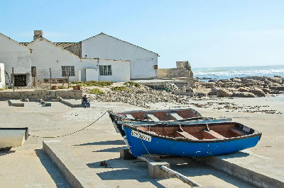 Blue fishing boat and harbour buildings at Hondeklip Bay on the Atlantic coast of Namaqualand, South Africa.