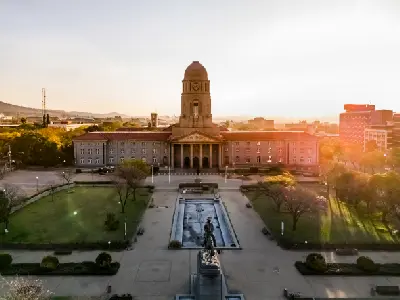 Pretoria City Hall at sunset with golden evening light, formal gardens and surrounding city buildings in Pretoria, Gauteng, South Africa.