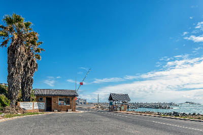 Harbour entrance at Yzerfontein with palm trees, harbour buildings, rock breakwaters and Atlantic Ocean waves along the West Coast of South Africa.