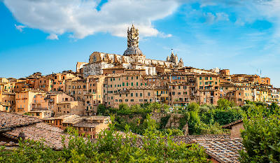 View over the historic centre of Siena in summer, with the Siena Cathedral visible at the centre.