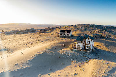 Aerial view of abandoned buildings and desert dunes in Kolmanskop ghost town, Namibia.