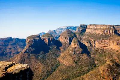 The Three Rondavels rock formations in Blyde River Canyon, Mpumalanga, South Africa, with layered sandstone cliffs and rugged canyon landscapes stretching into the distance.