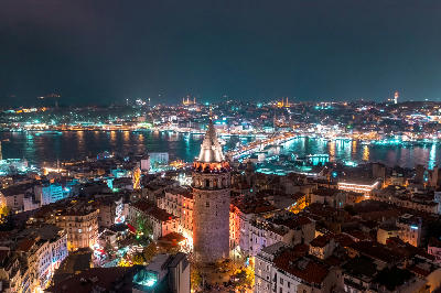 Night view of Galata Tower overlooking the Golden Horn and illuminated Istanbul skyline.