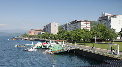 Toyako Onsen waterfront with hotels and lakeside promenade along Lake Toya in Hokkaido, Japan.