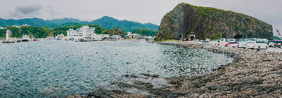 Olonko Rock next to Utoro Harbor in Shiretoko, Hokkaido, with boats, buses, and coastline visible