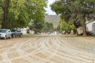 Tree-lined dirt road and historic buildings in Nieu-Bethesda, a village in the Eastern Cape Karoo of South Africa.