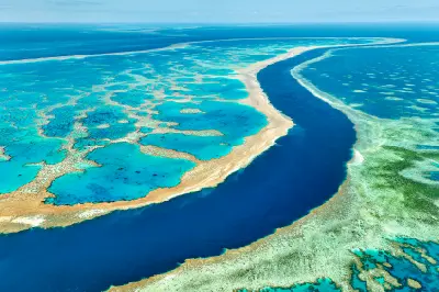 Aerial view of a deep blue channel between extensive coral formations on the Great Barrier Reef, Queensland, Australia.