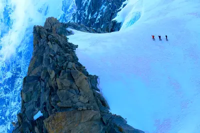 Climbers crossing a steep snowy ridge in the Mont Blanc massif in the French Alps.