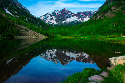Crater Lake near Aspen Colorado reflecting the Maroon Bells with still water, alpine forest, and snow-covered peaks in the Elk Mountains.