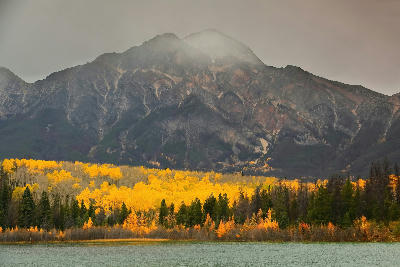 Patricia Lake with yellow aspen forest and Pyramid Mountain under cloudy sky