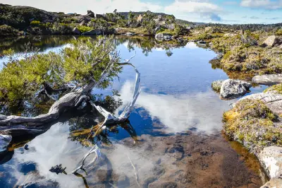 Still alpine tarn reflecting rocky mountains and vegetation on the Tarn Shelf in Mount Field National Park, Tasmania.
