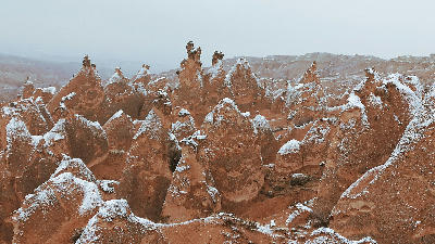 Winter view of snow-covered fairy chimney rock formations in Devrent Valley (Imagination Valley), Cappadocia, Turkey, with the surreal volcanic landscape blanketed in fresh snow.