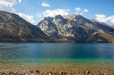 Clear water of Jenny Lake with rocky shoreline and the Teton Range in the background, Grand Teton National Park, Wyoming, USA.