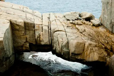 Natural Bridge spanning a narrow ocean channel between granite rocks in Torndirrup National Park near Albany, Western Australia.