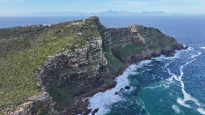 Aerial view of the dramatic cliffs of Cape Point with the lighthouse above the ocean in Table Mountain National Park, South Africa.