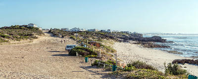 Coastal access track and rocky shoreline near Roman Beach and the Waenhuiskrans Cave trail in Arniston, South Africa.
