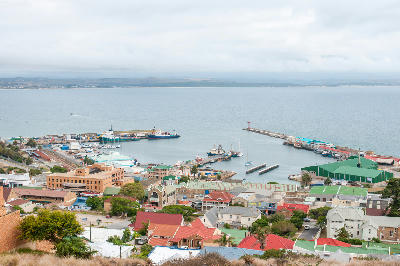 View across Mossel Bay Harbour showing fishing vessels, harbour infrastructure and the town centre in the Western Cape, South Africa.
