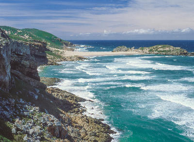 View across the cliffs, sandy neck and turquoise waters of Robberg Peninsula near Plettenberg Bay, South Africa.