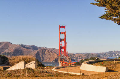 Golden Gate Bridge framed by foreground structures near Baker Beach with hills in the background