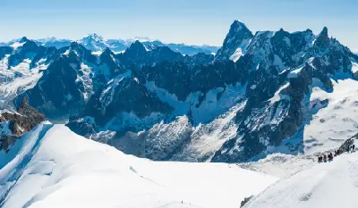 Climbers traversing the narrow snow ridge from Aiguille du Midi toward the Vallée Blanche glacier, French Alps.