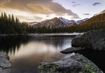 Bear Lake at sunrise with calm reflections and mountain peaks in Rocky Mountain National Park, Colorado.