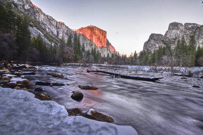El Capitan Yosemite from Valley View at sunset with Merced River flowing through snowy valley.