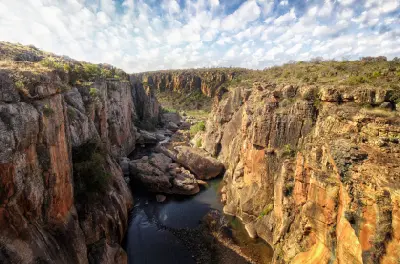 Sandstone gorge at Bourke’s Luck Potholes in Mpumalanga, South Africa, featuring steep rock walls, a narrow river channel, large boulders and rugged canyon scenery shaped by water erosion.