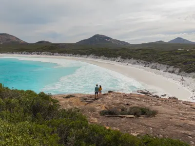 Couple overlooking turquoise water and white sand at Hellfire Bay in Cape Le Grand National Park, Western Australia.