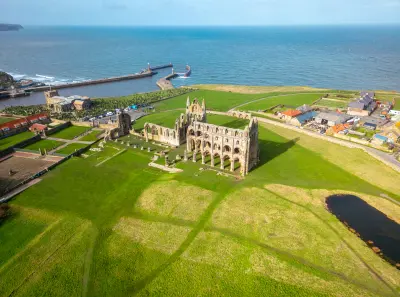 An aerial view of Whitby Abbey reveals its historic Gothic ruins overlooking Whitby Harbour and the North Sea on the East Cliff in North Yorkshire, England.