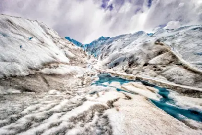 Meltwater channels flowing across the surface of Perito Moreno Glacier with blue ice and rugged textures in Patagonia, Argentina.