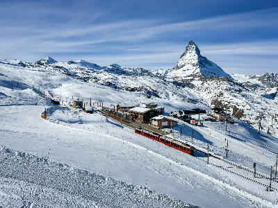 Train on Gornergrat cog railway at station Riffelberg above Zermatt town in Mattertal, Valais canton, Switzerland, in winter. Matterhorn mountain peak in background.