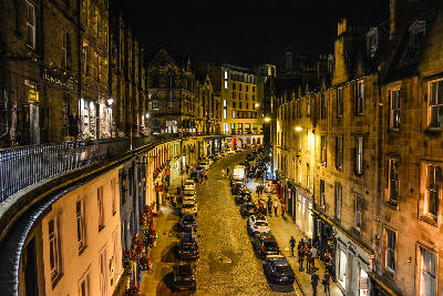 Victoria Street in Edinburgh at night with illuminated buildings and cobblestones.