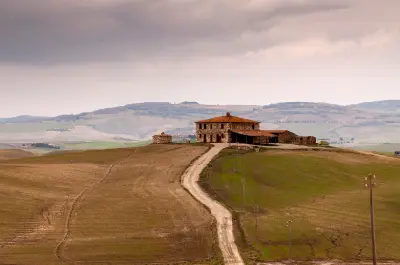 Farmhouse and winding dirt road at Podere Terrapille in the rolling hills of Val d’Orcia, Tuscany, Italy.