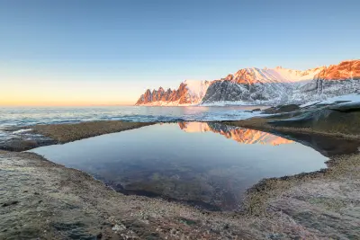 Okshornan peaks reflected in still coastal pool during sunset on Senja Island