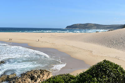 View across the broad sandy beaches and coastal dunes of Robberg Peninsula with waves rolling onto the shoreline near Plettenberg Bay, South Africa.