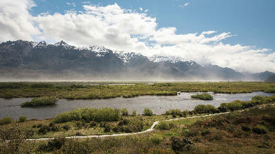 Glenorchy Lagoon wetlands with braided water channels and snow-capped mountains in the distance, South Island, New Zealand.
