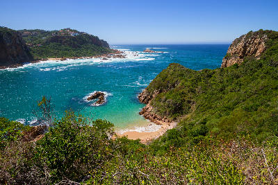 View across the cliffs and coastline of Featherbed Nature Reserve near Knysna Heads, with turquoise ocean water, rocky headlands and indigenous coastal vegetation.