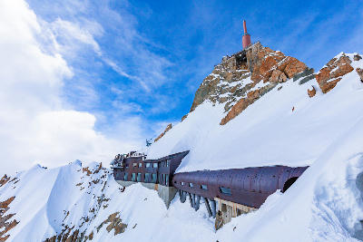 Aiguille du Midi summit buildings and tunnel on a snowy ridge above the Mont Blanc Massif.