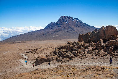 Hikers following the trail across the Saddle towards Mawenzi Peak (5,149 m) on Mount Kilimanjaro, Tanzania, at approximately 4,700 metres above sea level.