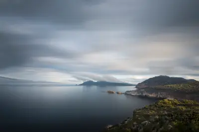 Moody storm clouds and calm ocean surrounding the rugged headlands viewed from Cape Tourville, Tasmania.