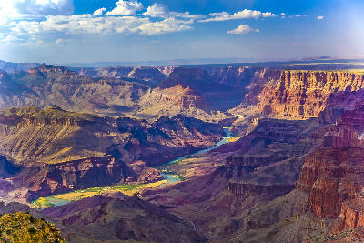 Grand Canyon South Rim with Colorado River winding through deep layered canyon formations under a blue sky