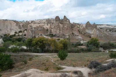 Scenic landscape of Love Valley in Cappadocia, Turkey, with fairy chimneys, volcanic rock formations, and walking trails beneath a cloudy sky.