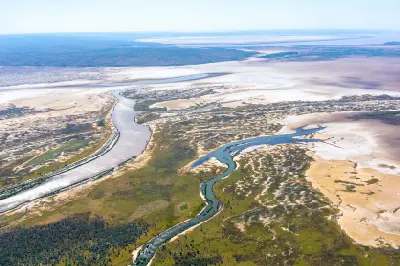 Aerial view of winding river and tidal channels crossing broad pale floodplains and wetlands near El Questro in the East Kimberley.