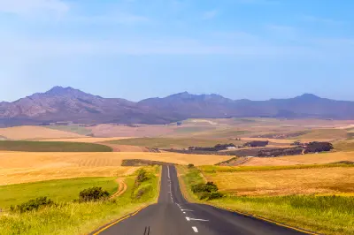 Long road through rolling farmland and mountain landscapes near Stanford in the Overberg region of the Western Cape, South Africa.