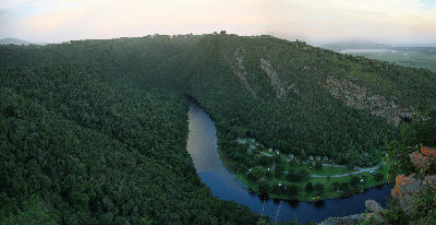 View across a forested river valley in Tsitsikamma, where dense indigenous forest surrounds a winding river below steep hillsides.