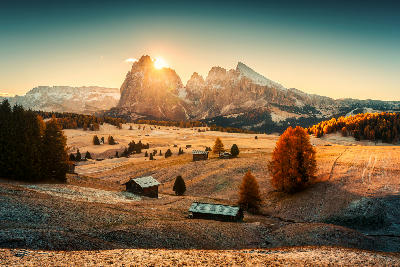 Autumn sunrise over Alpe di Siusi, with the Sassolungo and Sassopiatto peaks above golden grass hills in the Dolomites, Italy.